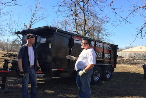 two men talking in front of a rental dumpster